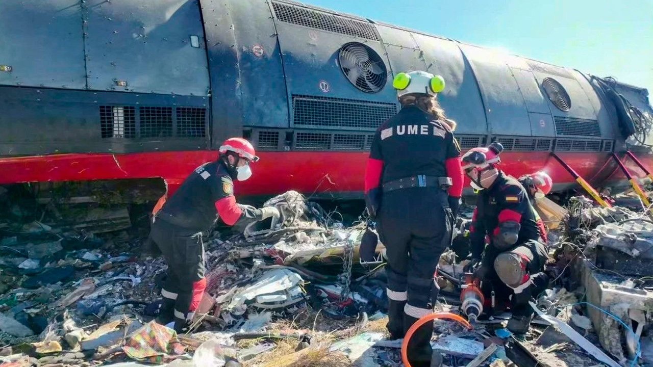 Personal de rescate con uniformes de la UME revisan los restos de un tren de alta velocidad tras una colisión
